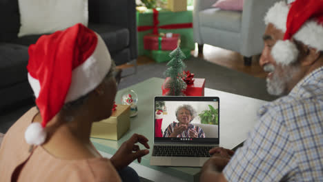 feliz pareja de adultos mayores afroamericanos en llamada de video portátil con una amiga en la época de navidad