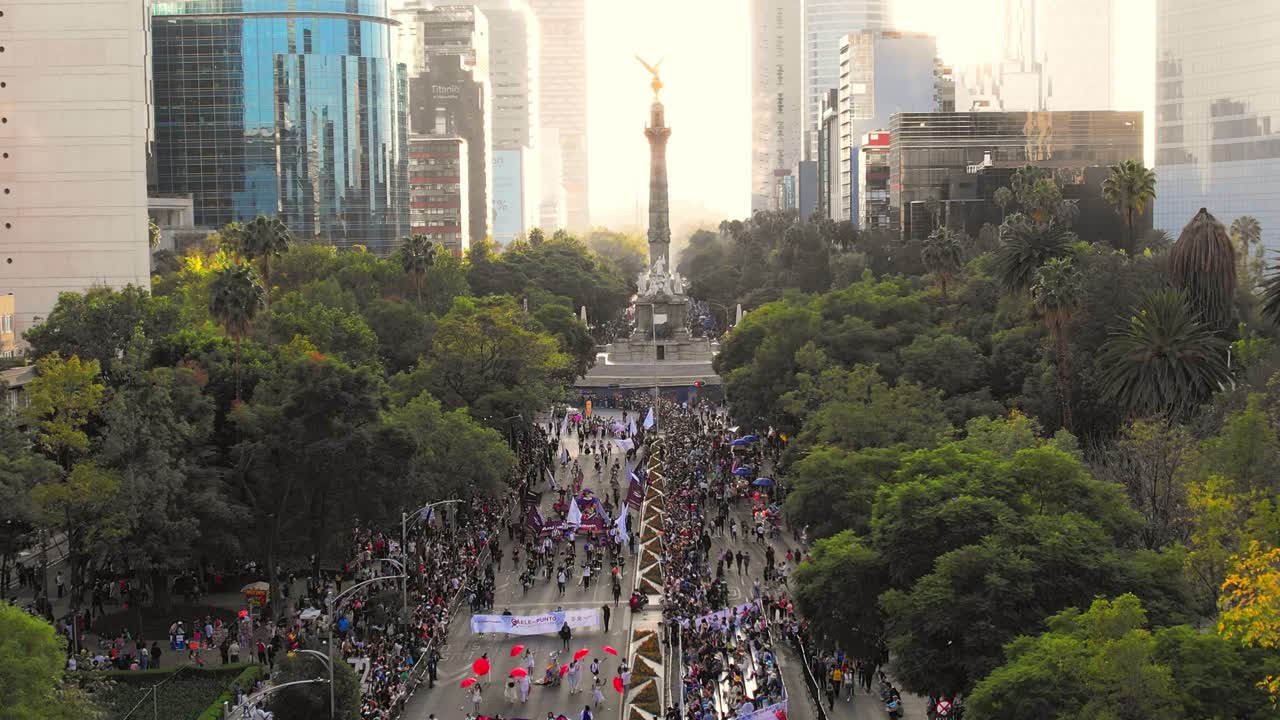 Drone shot of Day of the Dead parade and celebration on the streets of Mexico City with Independence victory column monument in background