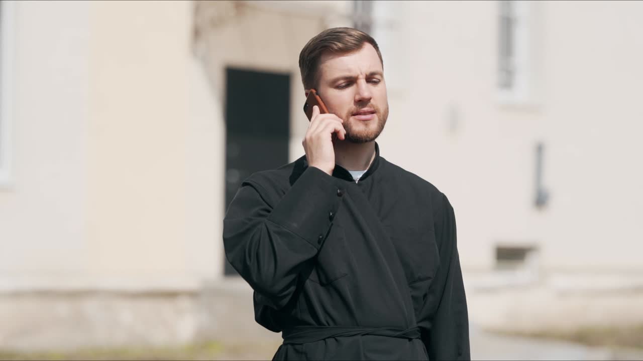 멋진 젊은 사제가 전화 통화를 하고 있다