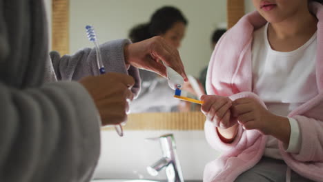 Feliz-Madre-E-Hija-De-Raza-Mixta-Cepillándose-Los-Dientes-En-El-Baño.