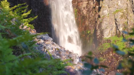 tiro largo medio de ángulo bajo de la base de la cascada rocosa njupeskär, sumergiendo agua dulce entre el cañón erosionado, en el parque nacional fulufjället, en särna, suecia