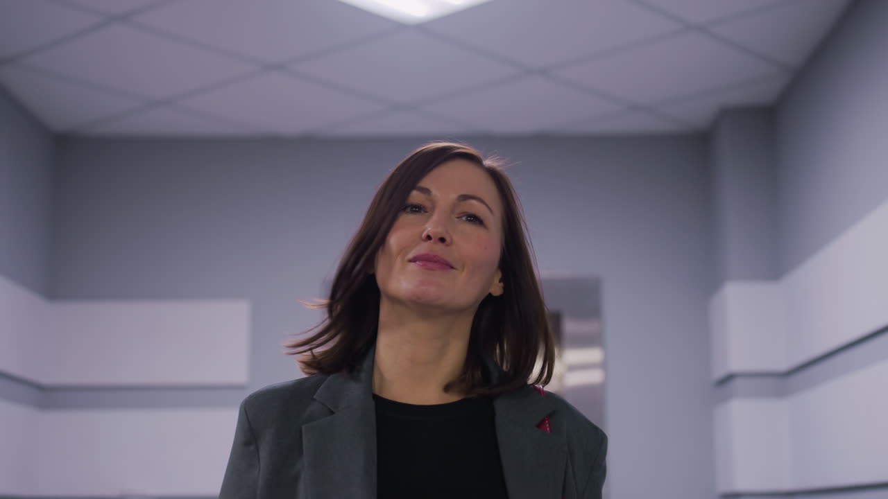 Businesswoman smiling confidently in elevator lobby of modern office building. Professional, focused, and successful woman in business attire ready for work. Empowered female leadership