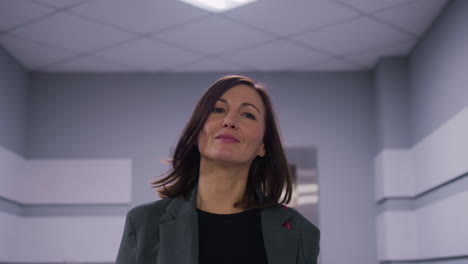 businesswoman smiling confidently in elevator lobby of modern office building. professional, focused, and successful woman in business attire ready for work. empowered female leadership