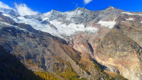 Saastal-Saas-Fee-Switzerland-tram-ride-top-of-Swiss-Alps-glacier-mountain-peaks-summer-morning-stunning-vibrant-clear-blue-sky-alpine-valley-fresh-snow-dusting-Zermatt-Alphabel-pan-right-slowly