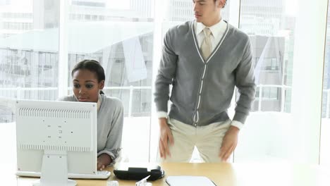 joven mujer de negocios en una computadora teniendo una discusión con un colega