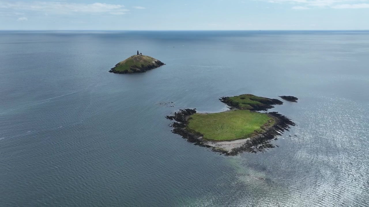 Úžasné irské letecké záběry: Maják Ballycotton, letecký záběr s oddálením od ostrovů a majáku na okraji divokého Atlantského oceánu, Hrabství Cork, Irsko. Epické.