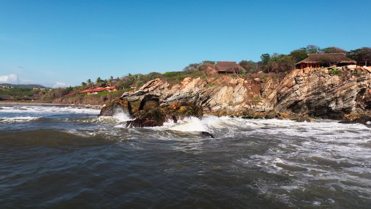 las olas de retroalimentación chocan y salpican alrededor de acantilados rocosos frente a la costa de puerto escondido, oaxaca, méxico.