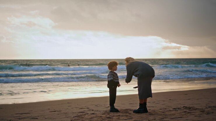 Parent scolding little boy on beach. Young mother talking boy resting shore