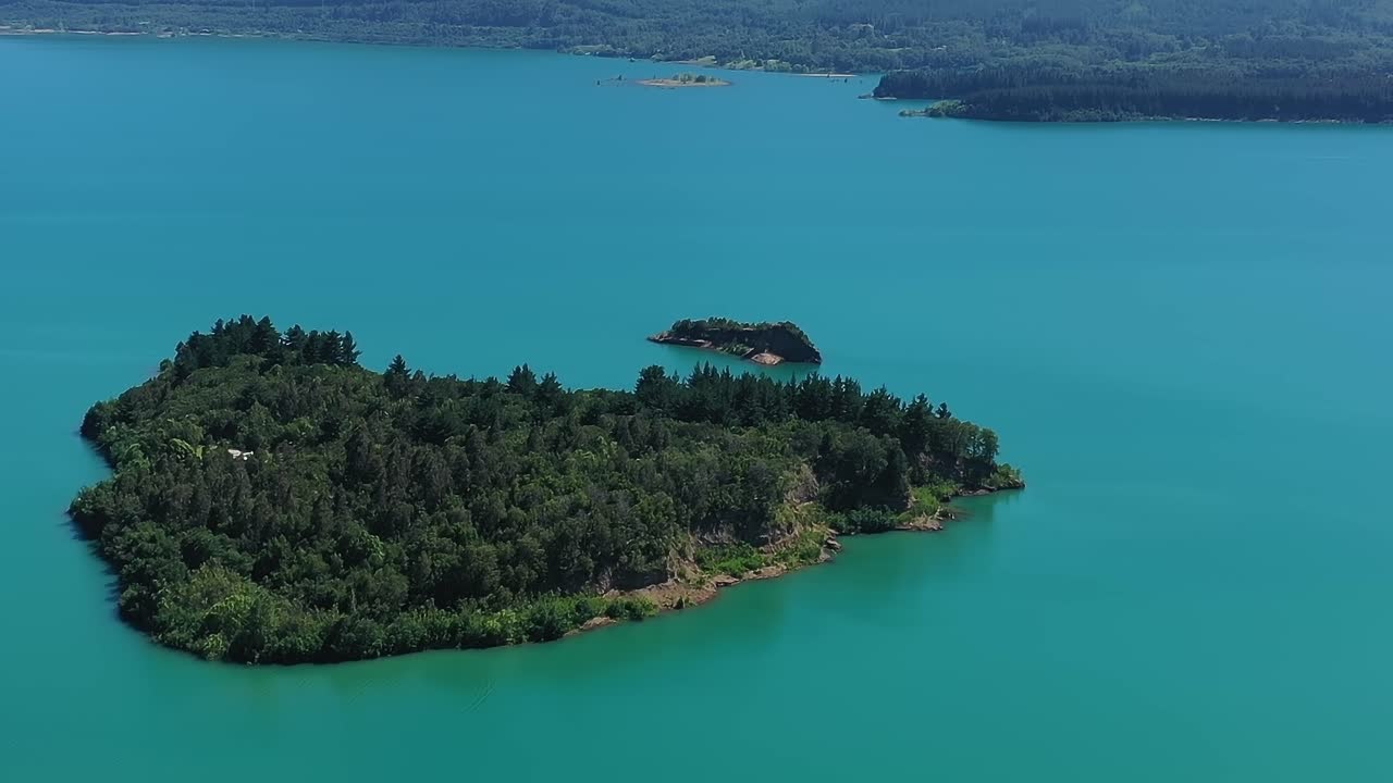 Il Lago Colbún in Cile mostra un'isola verde in una giornata di sole.