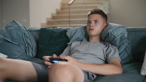 teenage boy playing video game on a couch