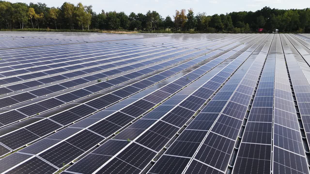 Wide aerial drone footage of multiple rows of solar panels in a renewable energy farm in the Netherlands