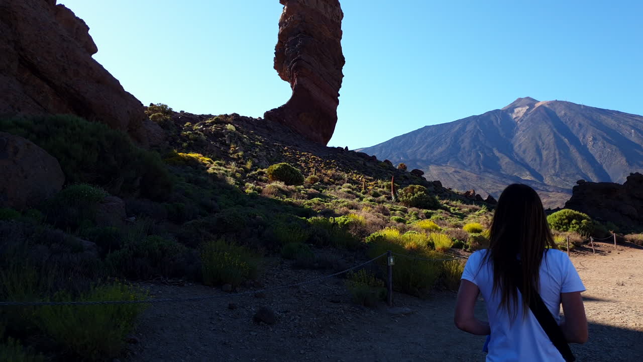 Tourist walking towards Roque Cinchado rock formation in Teide national park, Tenerife, canary islands, spain, slow motion