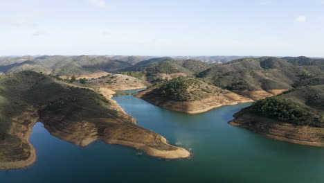 vuelo de drones sobre el agua azul del lago santa clara y las montañas en la región del algarve en portugal