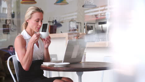 mujer de negocios en una mesa en un café usando una computadora portátil