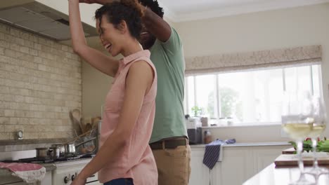 happy biracial couple dancing together in kitchen