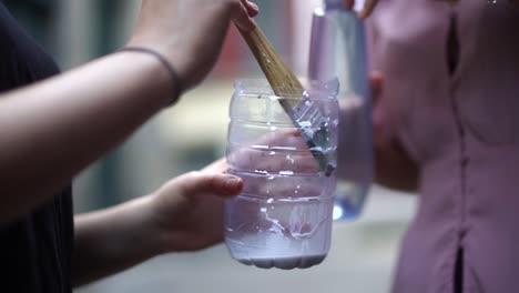 chicas vertiendo agua en una botella de plástico cortada con pegamento