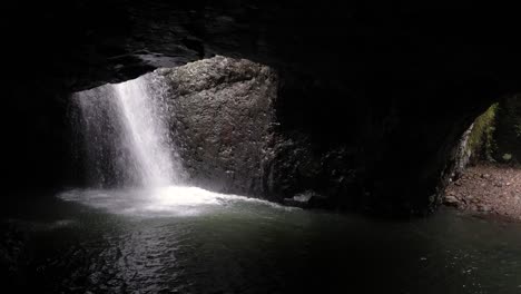 View-of-waterfall-and-Cave-Creek-from-inside-Natural-Arch-Cave,-Natural-Bridge,-Springbrook-National-Park