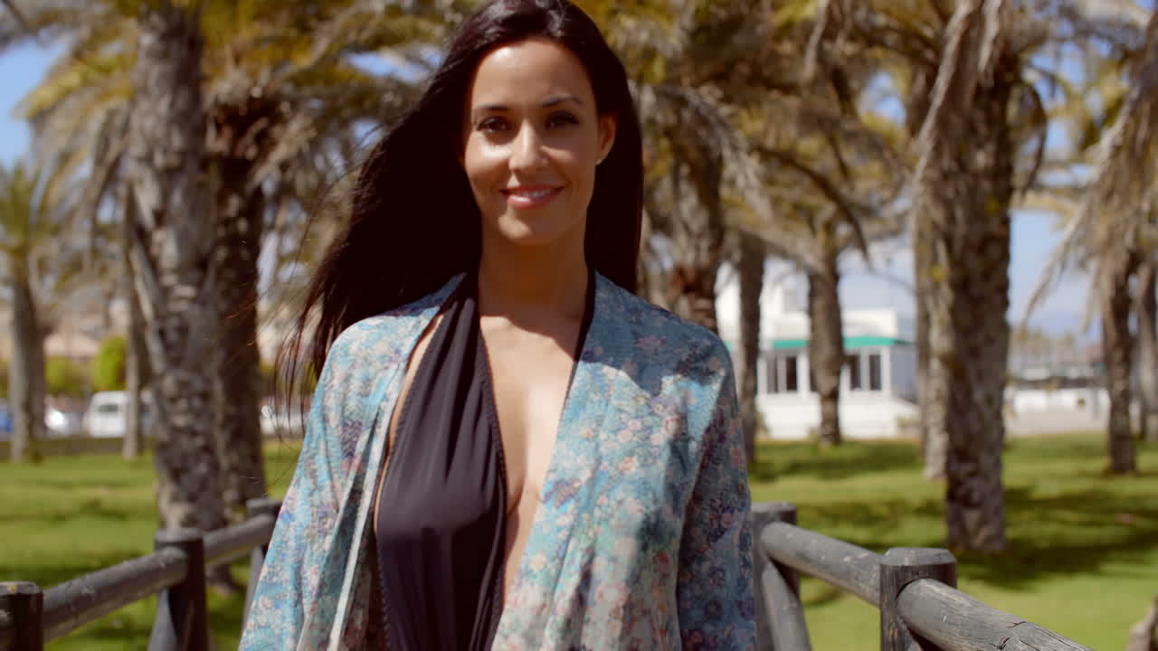 mujer pasando por un camino de playa con barandillas de madera