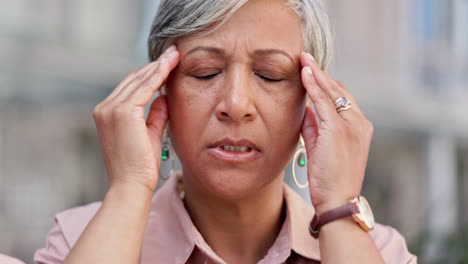 mujer mayor en los negocios con dolor de cabeza al aire libre