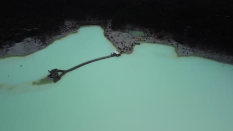 aerial view of the acidic lake of kawah putih with tourists visiting below in west java, indonesia