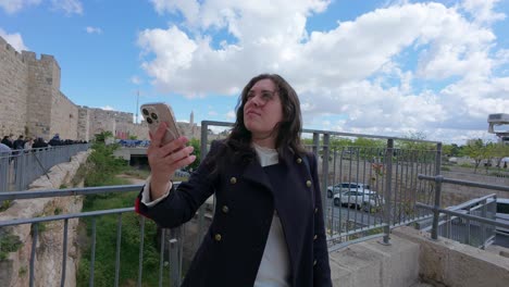 tourist using phone beside historic wall in jerusalem. slow motion.