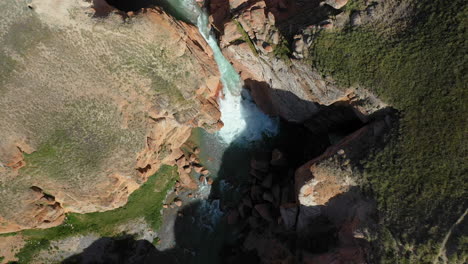 epic revealing drone shot of a small waterfall leading from a river near the kell-suu lake in kyrgyzstan