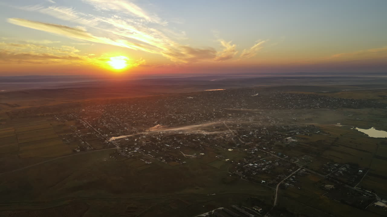 Aerial drone view of village in Moldova at sunset. Few columns of smoke from fires, wide fields