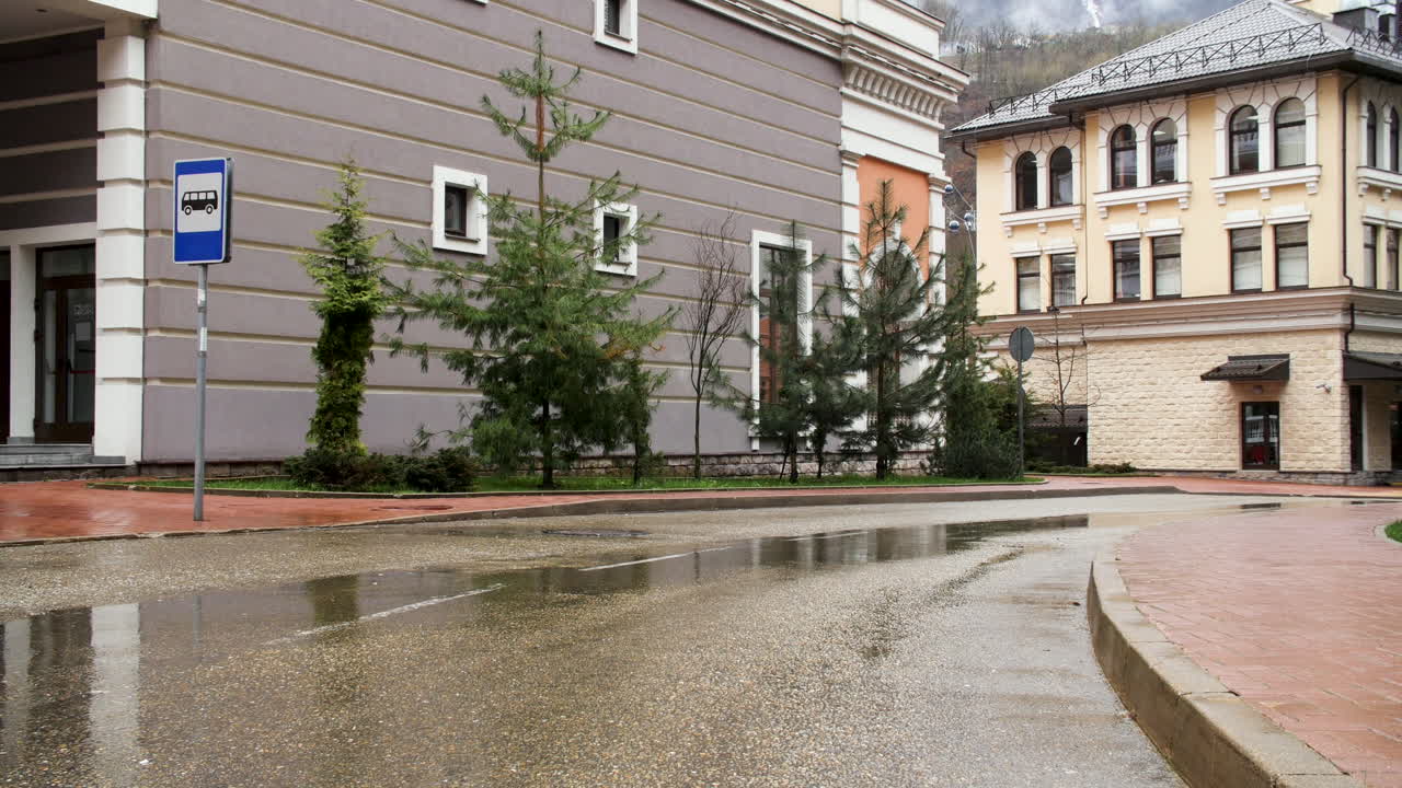 Scena di strada piovosa con fermata dell'autobus ed edifici