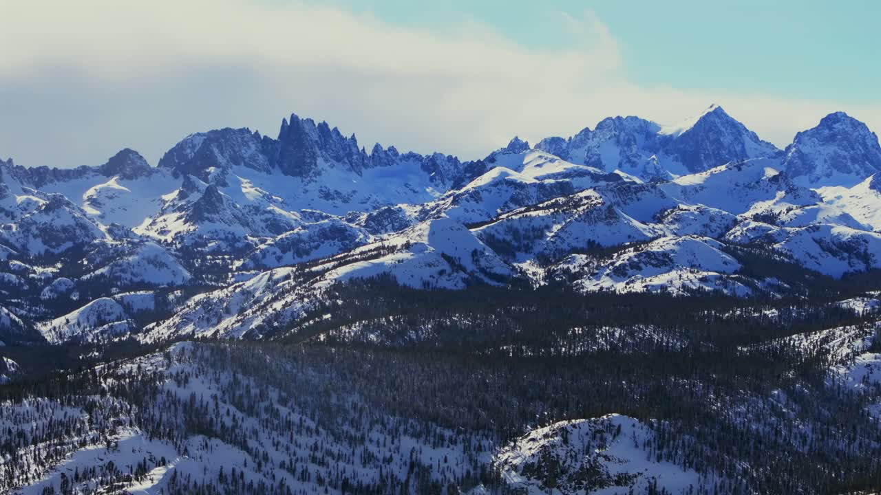 Minarets Jagged Peaks Mountain Summit Vista panoramic landscape aerial drone winter Mammoth Mountain Ski Resort California Inyo National Forest the Hemlocks sunny blue skies cloudy pan left motion
