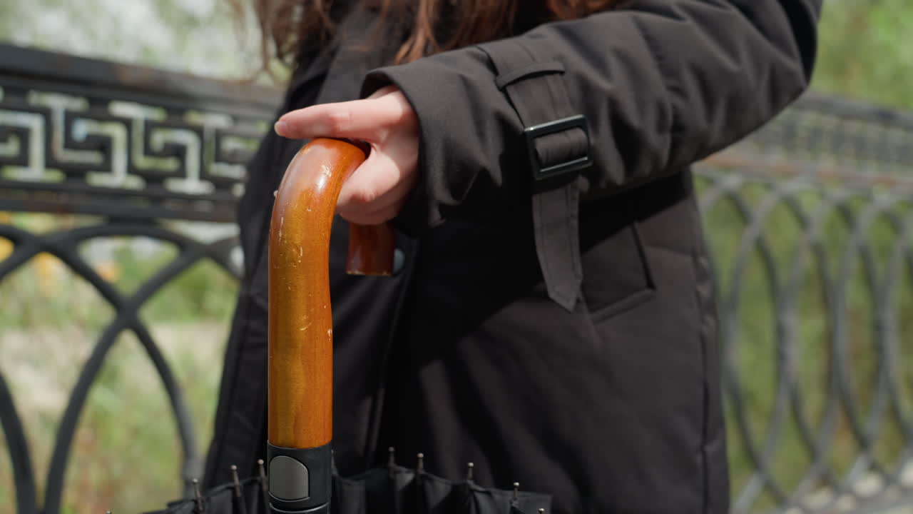 Beslutsom kvinde, der går i regnen. Kaukasisk kvindelig rejsende bevæger sig støt under en overskyet himmel. Resolut kvinde med paraply med træhåndtag går op ad trapperne i parken i trist regnvejr.