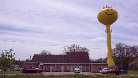 un tanque de agua con cara sonriente se eleva sobre un motel sórdido y deprimente