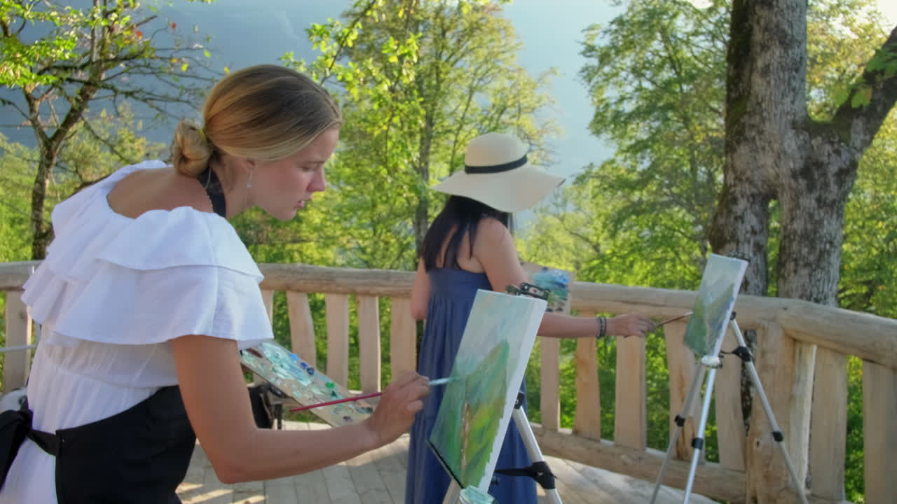 두 명의 여성이 야외에서 풍경을 그리고 있습니다.