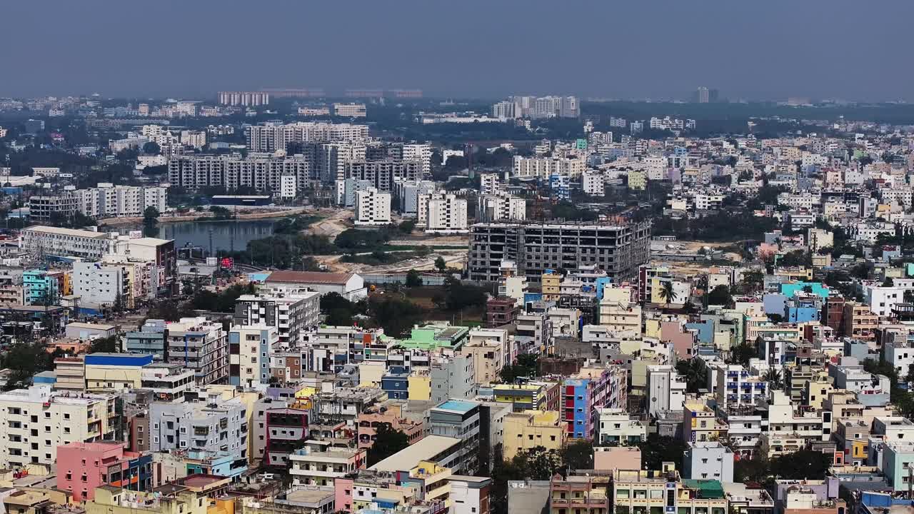 Edifici residenziali con appartamenti, edifici in costruzione e il Lago Kattamysamma a Suraram, Hyderabad, Telangana, India. Di giorno, ripresa all'indietro, ripresa con drone, 4K