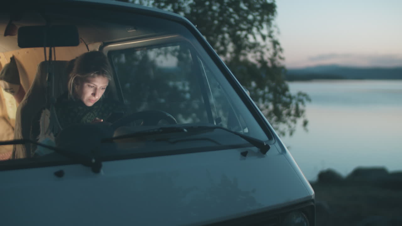 저녁 에 휴대 전화 를 사용하는 밴 에 있는 여자
