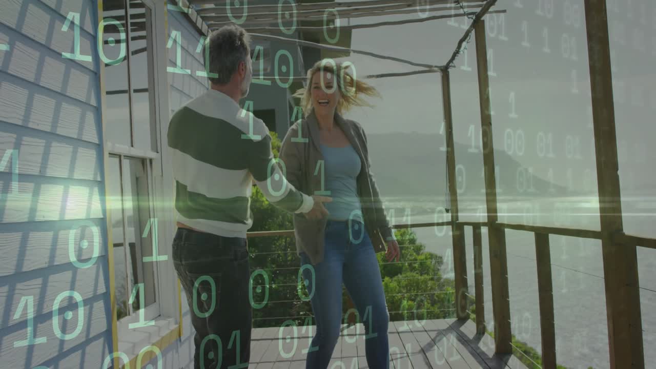 Man lifting woman's hand overhead leading spin dancing on balcony with tech binary overlay drifting