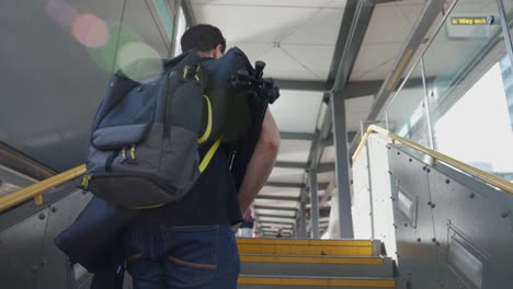 videógrafo llevando equipo de cámara por el tramo de escaleras
