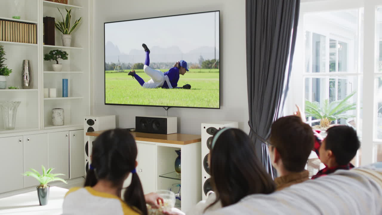 집에서 함께 앉아서 tv에서 야구 경기를 보는 행복한 가족의 구성