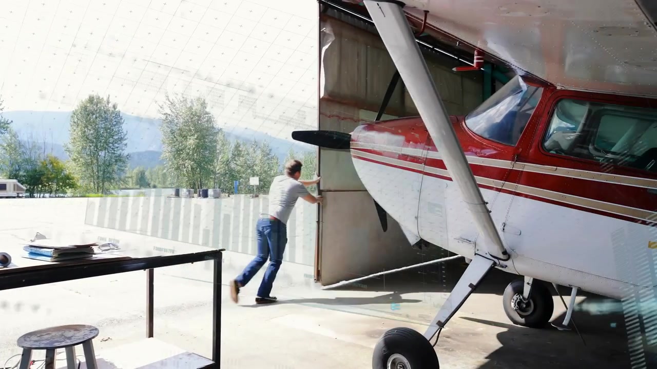 Uomo che spinge la porta di un hangar in un hangar per aerei, con grafici di dati animati e icone di manutenzione.
