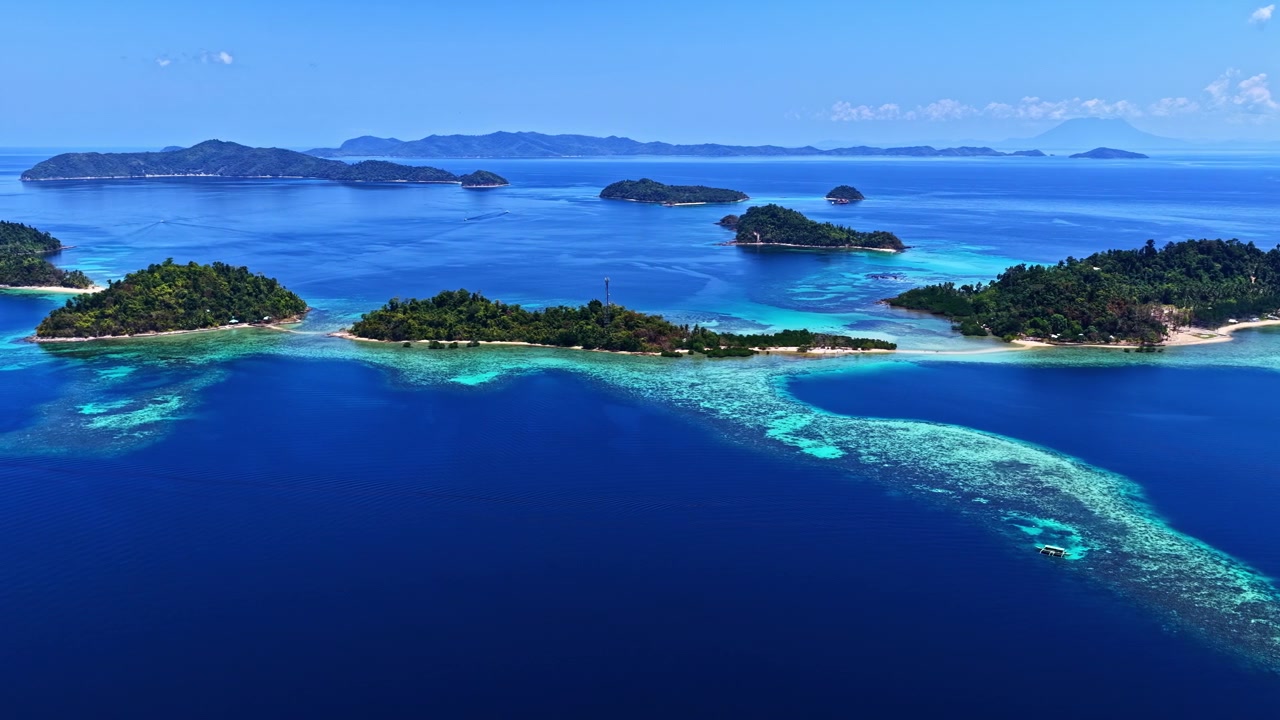 澄み切った青空の下、フィリピンのポートバートンビーチ近くのターコイズブルーの海と小さな島々の空撮。