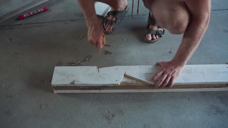 man drawing line pattern on wood plank for cutting