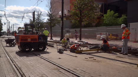 slow motion video of construction workers lining up new railroad tracks in a city.