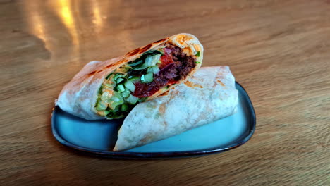 Leckerer-Burrito-Auf-Schickem-Teller,-Wrap-Aus-Nächster-Nähe,-Abendessen-Auf-Holztisch-Serviert