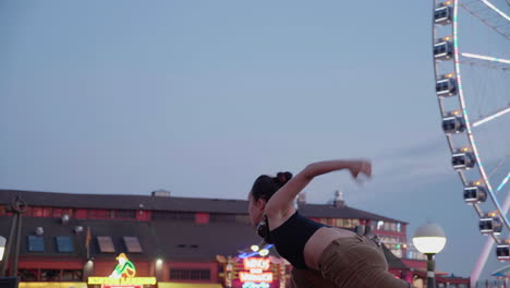 Young,-female,-contemporary-dancer-near-an-urban-Ferris-wheel