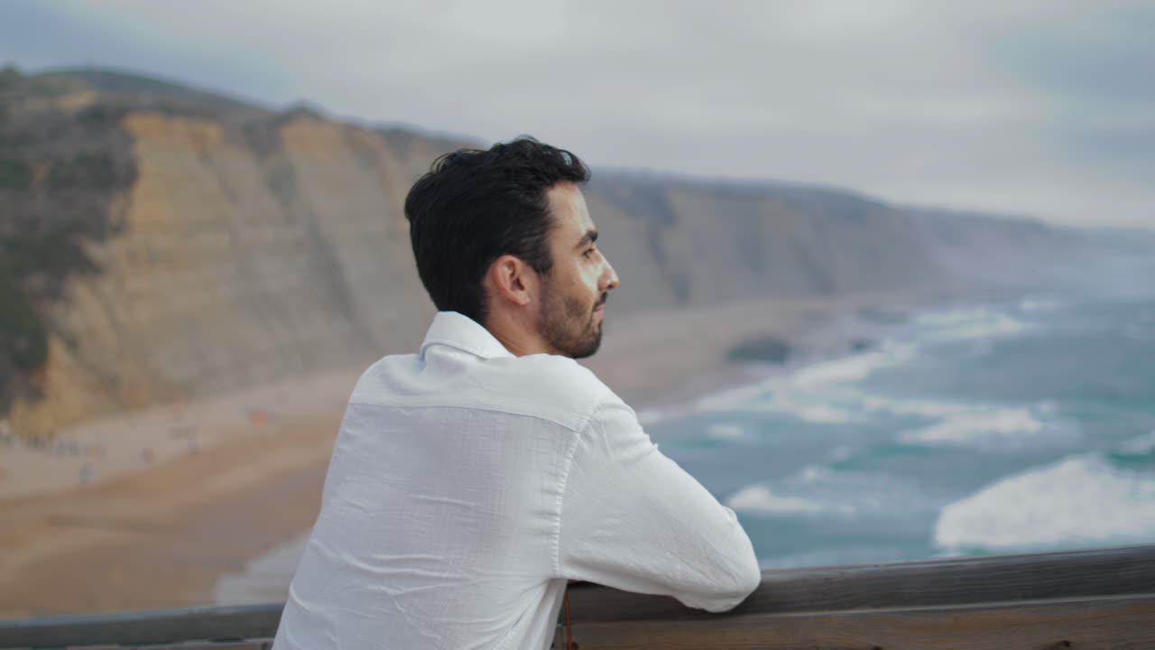 hombre satisfecho mirando la costa del océano de cerca. turista adulto disfrutando del mar tormentoso