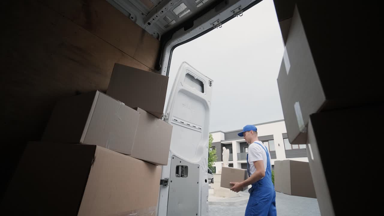 dos jóvenes trabajadores de una empresa de mudanzas descargan cajas y muebles del minibús en la casa del cliente