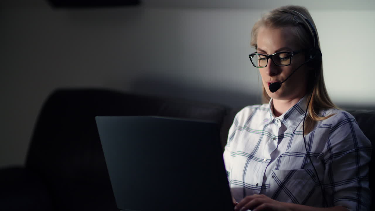Female Entrepreneur Using Laptop While Talking On Headset In Office