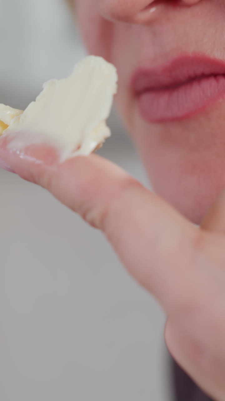 vista de cerca de la mano de una persona que sostiene la mantequilla cremosa en el dedo, acercándola a la nariz mientras percibe el aroma con expresión satisfecha en la cocina moderna