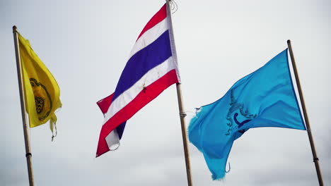 waving flag of thailand and koh phi phi island during windy day and cloudy sky