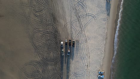 4wd vehicles parked on a beach with the ocean waves lapping the shoreline