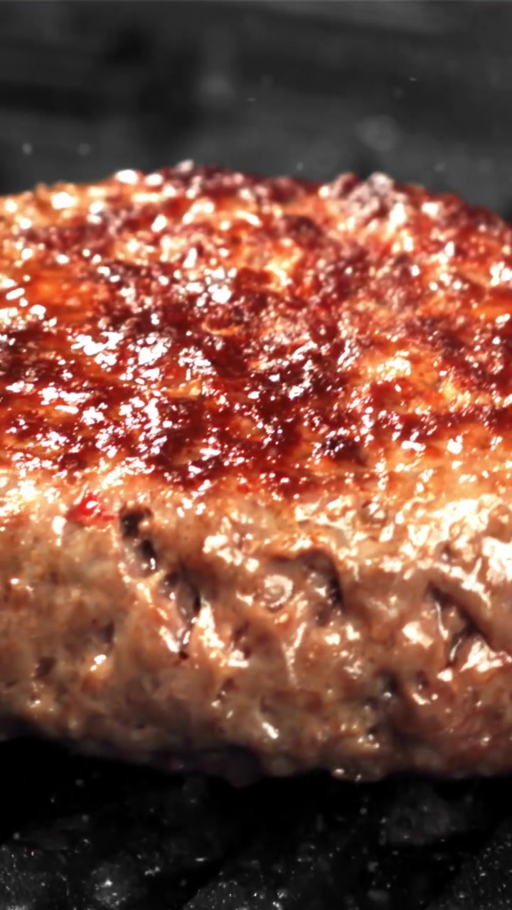 Primo piano di un hamburger che sfrigola su una griglia calda